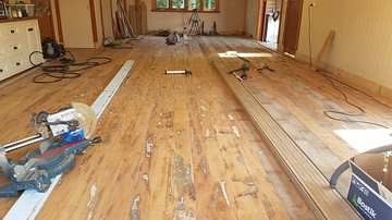 Recycled hardwood flooring part-laid across a room
