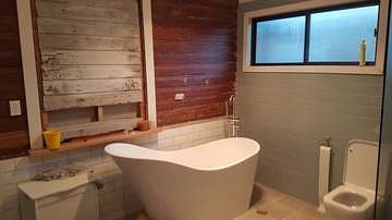 Renovated bathroom with freestanding bath and timber feature wall