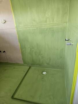 Waterproof membrane applied across bathroom floor and shower base